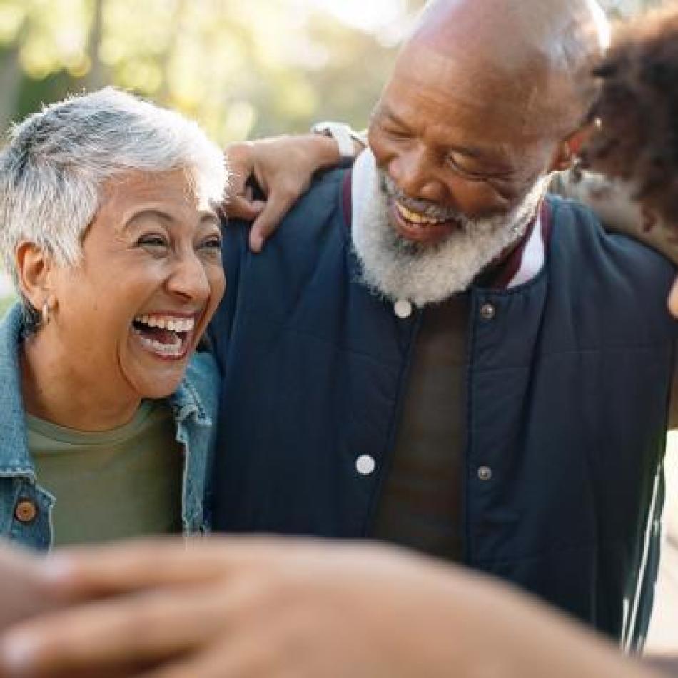 Photograph: Happy multi-generational family embracing and laughing outdoors.